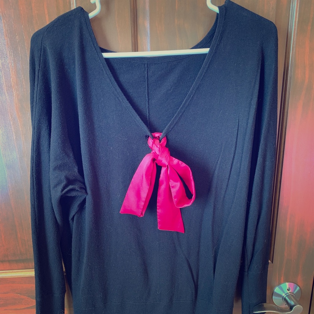 Black longer sweater with hot pink tie in back.